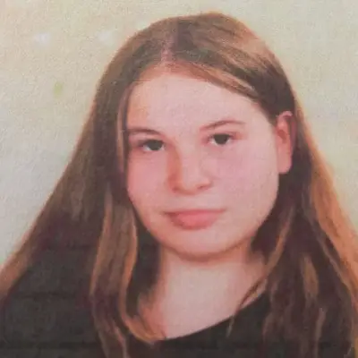 Eine junge Frau mit braunen Haaren, Sie ist im Portrait zu sehen und ihre Haare über ihr linkes Ohr hängen.